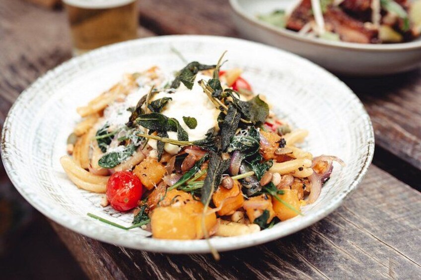 Une assiette de pâtes, avec des légumes verts, du fromage et une tomate rouge. 2