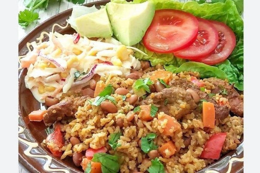 Un plato de comida con arroz, frijoles, carne y verduras. 1