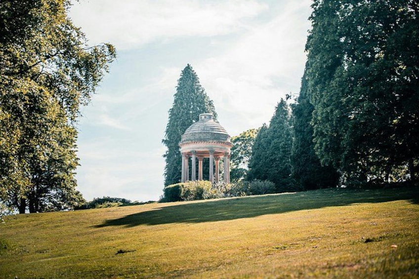 A gazebo in a park with trees and a grassy field. 3