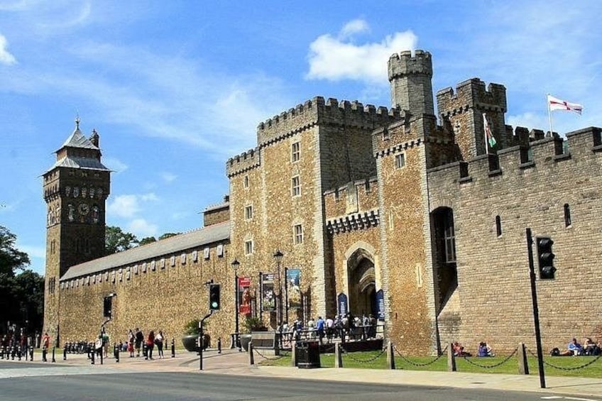 Een historisch kasteel met een klokkentoren, een rondbogige ingang en vlaggen. 4