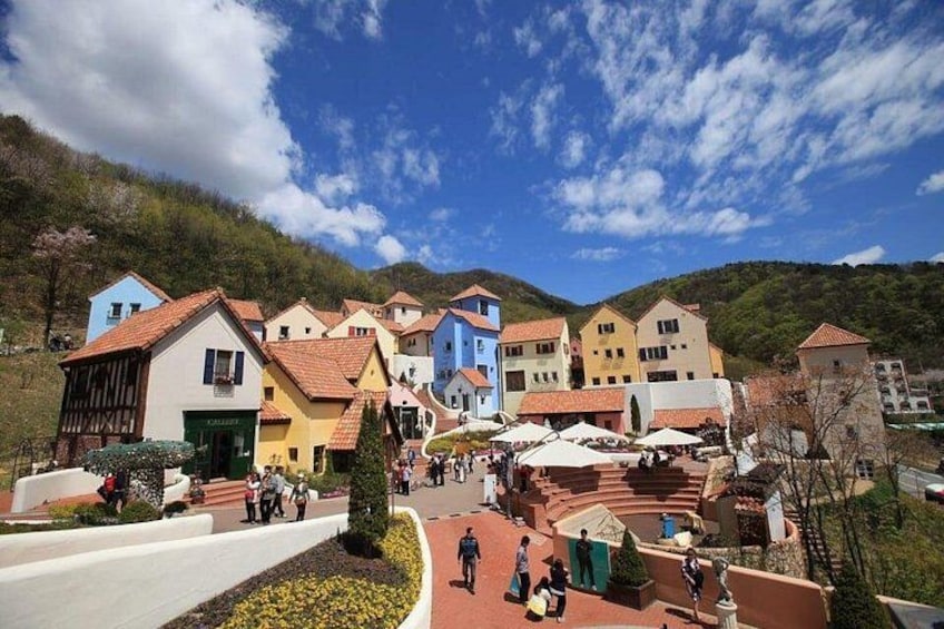 A village with colorful houses, a central square, and a hillside in the background. 3