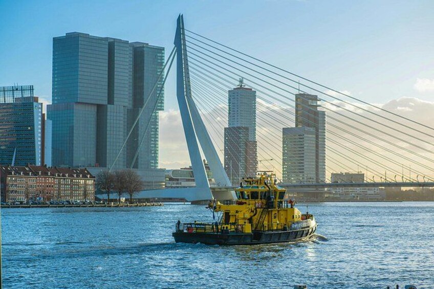 A tugboat on a river with a modern bridge and high-rise buildings in the background. 2