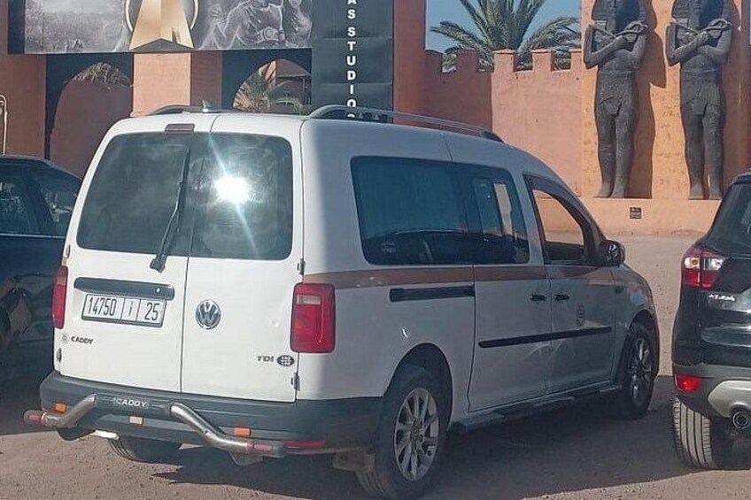 A white van parked in front of a building with a large mural. 3