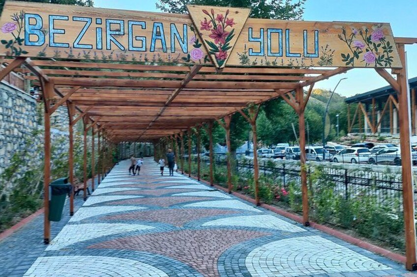 Un pasaje cubierto con piso de mosaico que conduce a la entrada de un edificio, identificada con el cartel 'BEZIRGAN YOLU'. 3