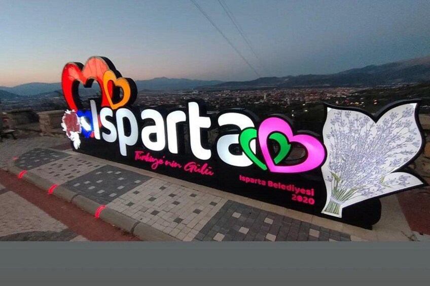 Un letrero con la palabra 'spart' y un símbolo de corazón, mostrando una vista de la ciudad al fondo. 5