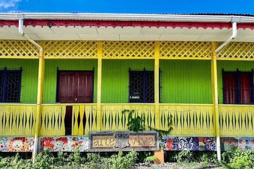 A colorful house with a green and yellow facade, a decorative balcony, and a tiled front. 5