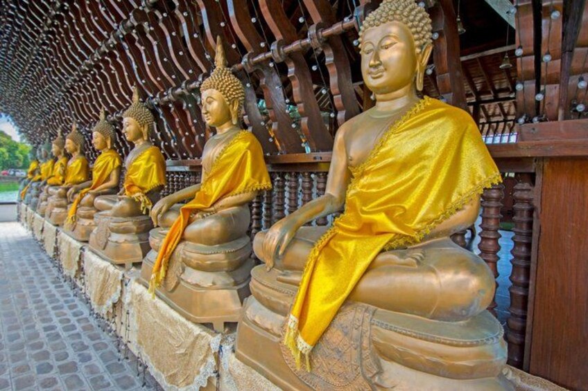 Une rangée de statues de Bouddha dorées, assises sur des piédestaux, sous un toit en bois. 3