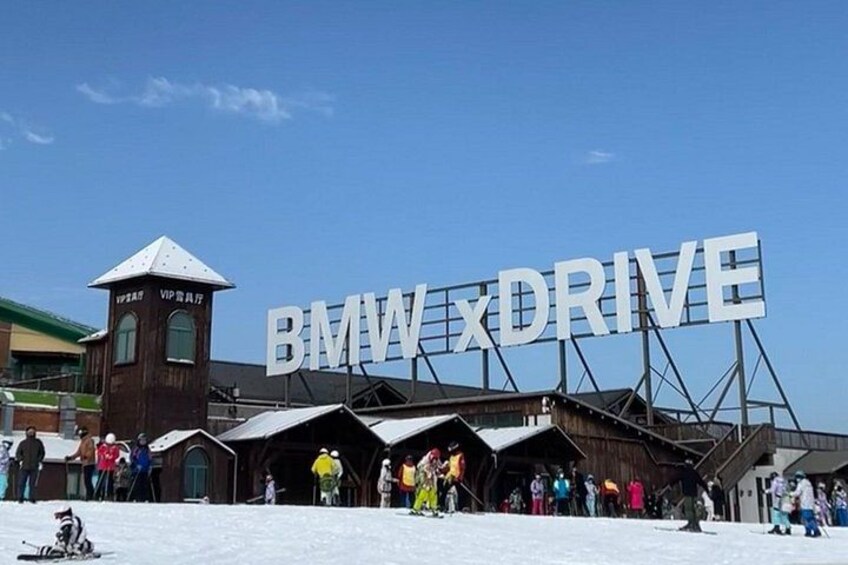 A snowy scene with a large sign reading 'BMW x DRIVE' and a ski lift in the background. 5