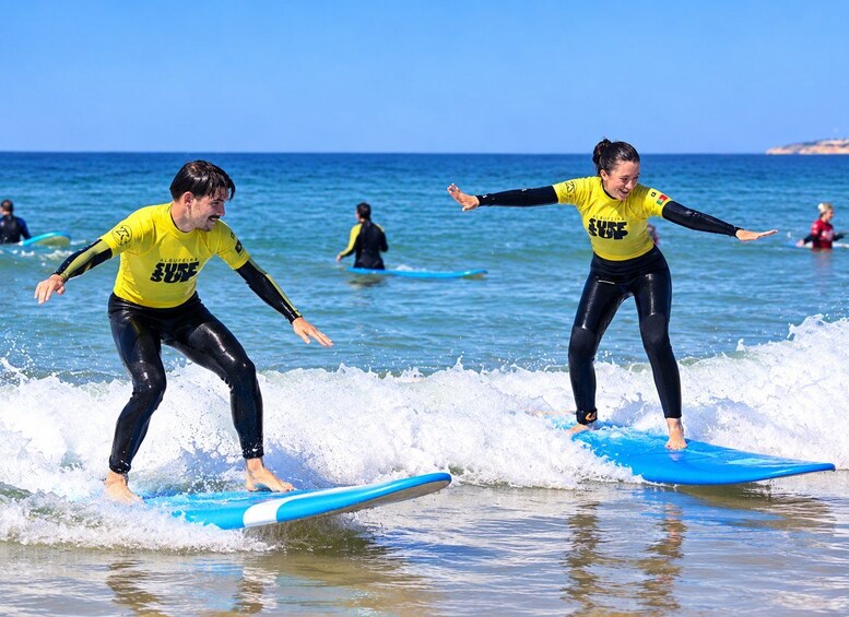 Two people surfing on blue boards in the ocean. 5