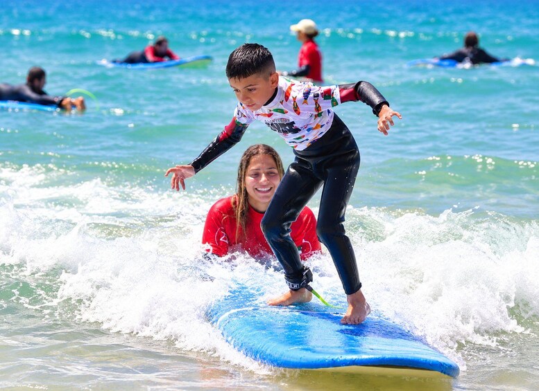 A person surfing on a wave with a child learning to surf nearby. 4
