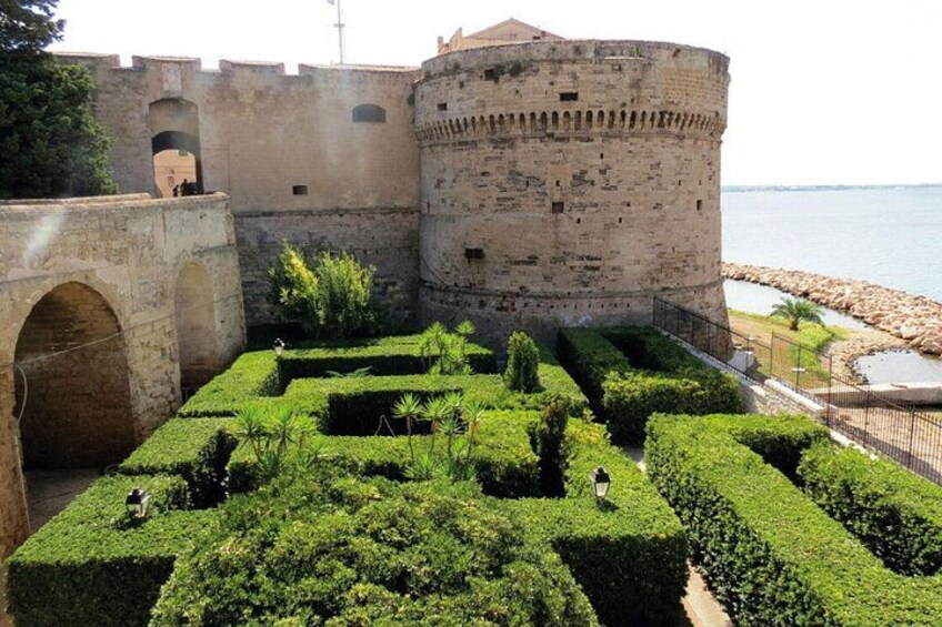 A historic castle with a moat, a round tower, and a well-maintained garden. 2