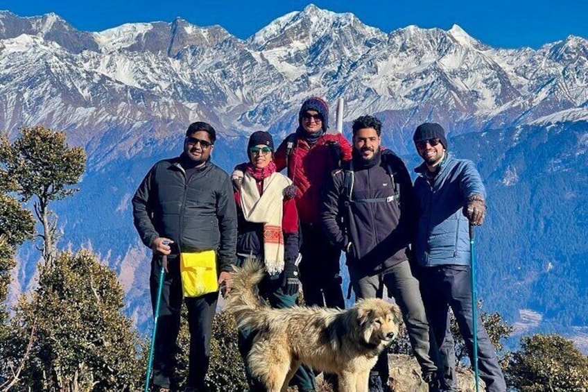 A group of people standing on a mountain with snow-capped peaks in the background. 1
