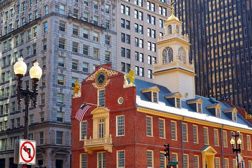 A red brick building with a clock tower, an American flag, and a gold statue on the roof. 5