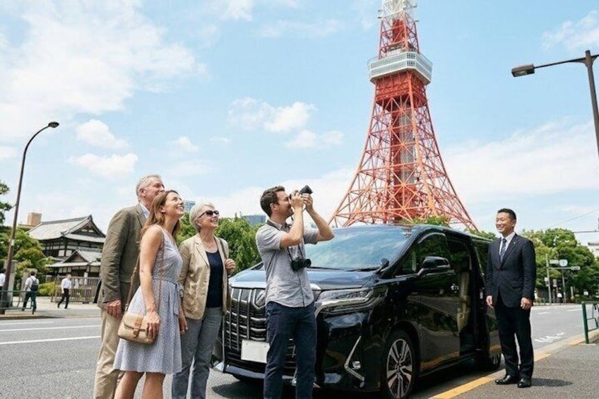 Un gruppo di persone che scatta una foto con un'auto nera davanti a una torre rossa. 1