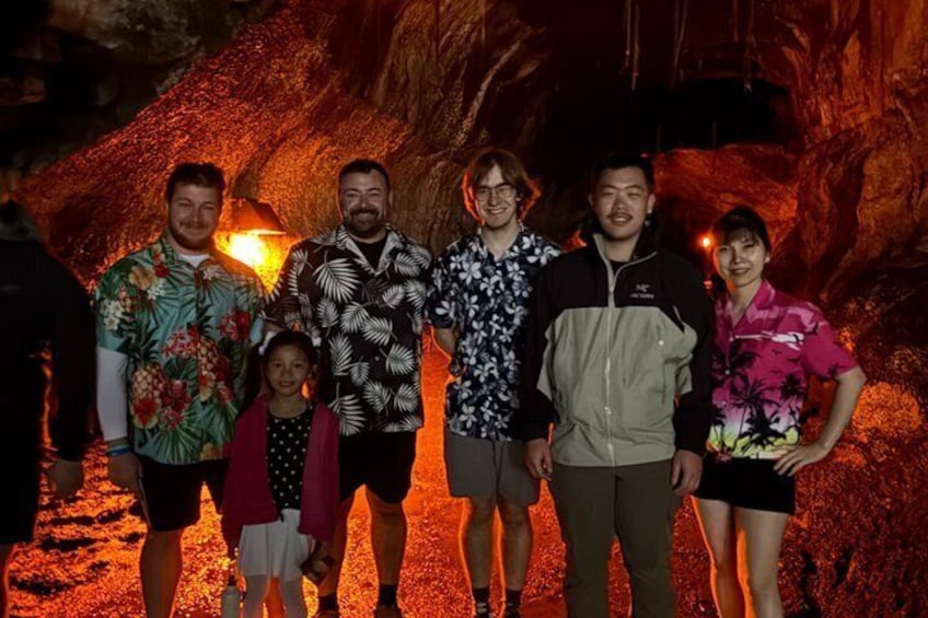Un groupe de personnes se tient devant l’entrée d’une grotte, où l’on peut voir des formations rocheuses d’un orange éclatant. 3