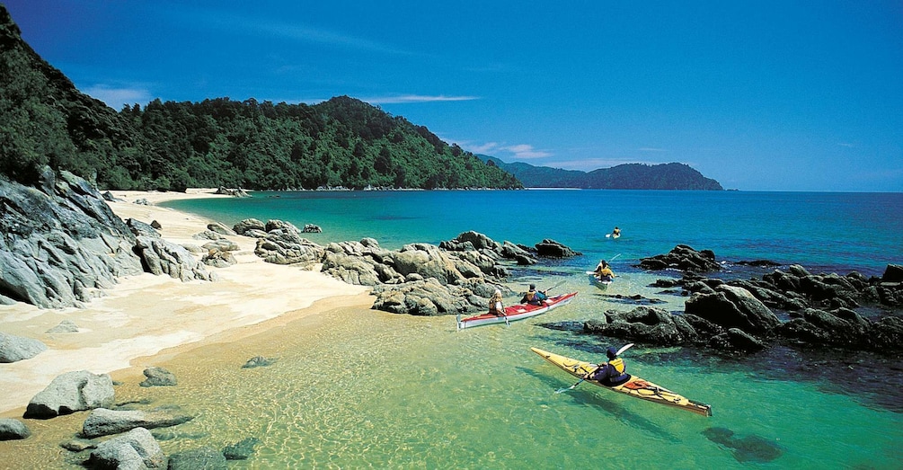 A beach with kayaks and people paddling. 2