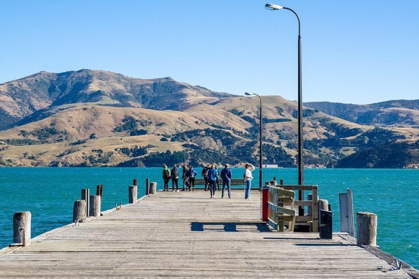 A wooden pier extending into a lake with people standing at the end. 2