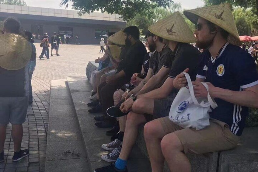 People sitting on a bench in an outdoor area with a building in the background. 3