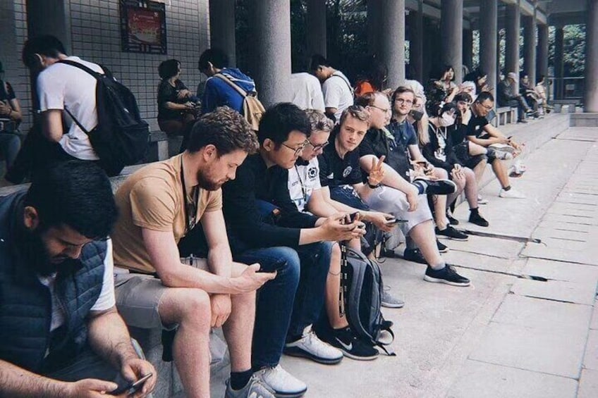People sitting on benches along a sidewalk. 5