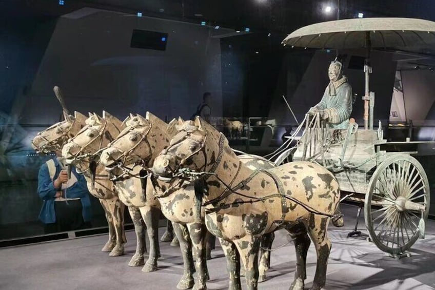 A historical display of chariots with horses and a seated figure. 1
