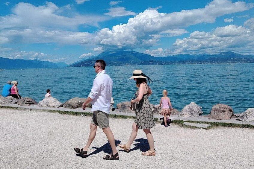 Un couple se promène le long d’un sentier au bord du lac, avec des rochers et un ciel dégagé. 2