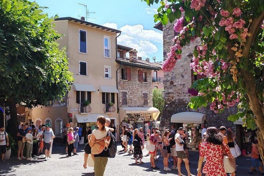 Une rue animée, bordée de piétons, de bâtiments historiques et d’arbres en fleurs. 3
