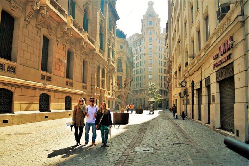 Una calle adoquinada bordeada de edificios históricos, algunos peatones y una jardinera grande en el centro. 2