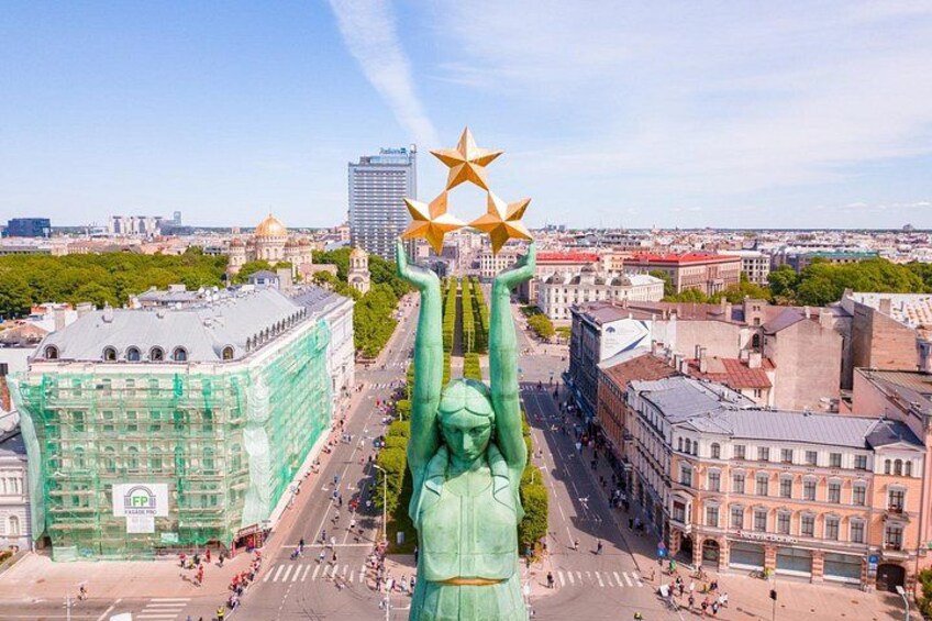 Eine Statue mit einem Stern auf dem Kopf, umgeben von Gebäuden und einem klaren Himmel. 1