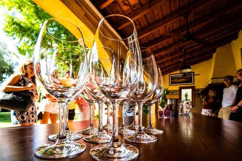 Wine glasses on a wooden table in a restaurant with a yellow awning and wooden ceiling. 1