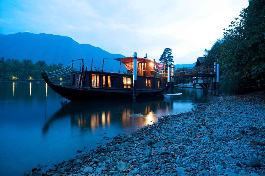 A boat docked at a lakeside pier with a mountainous backdrop. 3