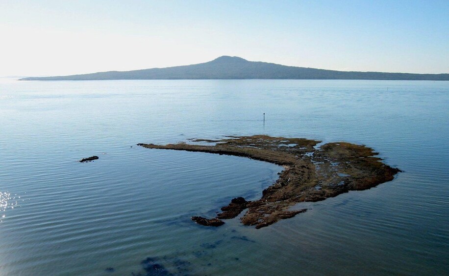 A calm lake with a small island in the center and a mountain in the background. 4