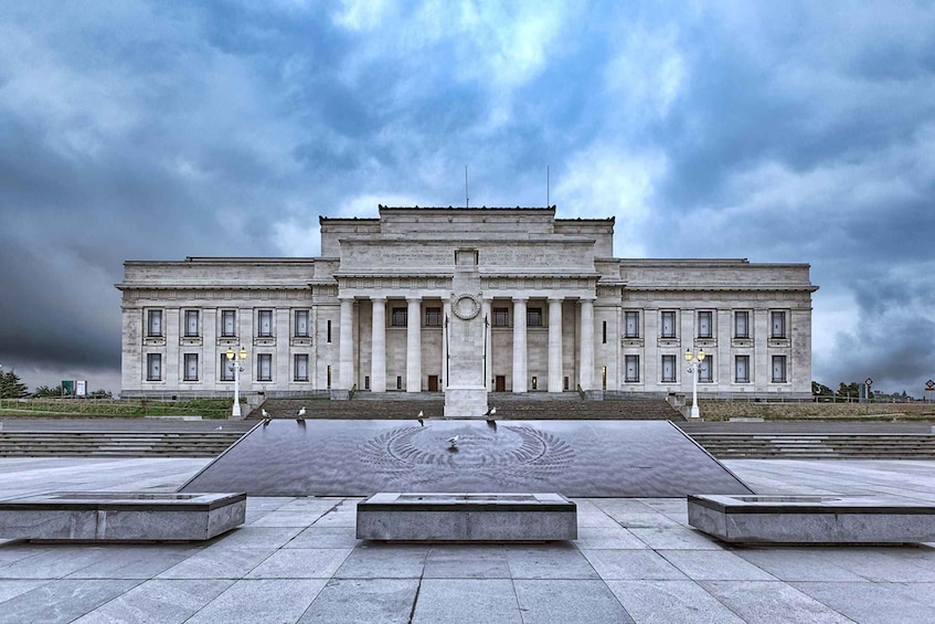 A large neoclassical building with a central circular fountain and steps leading up to it. 5