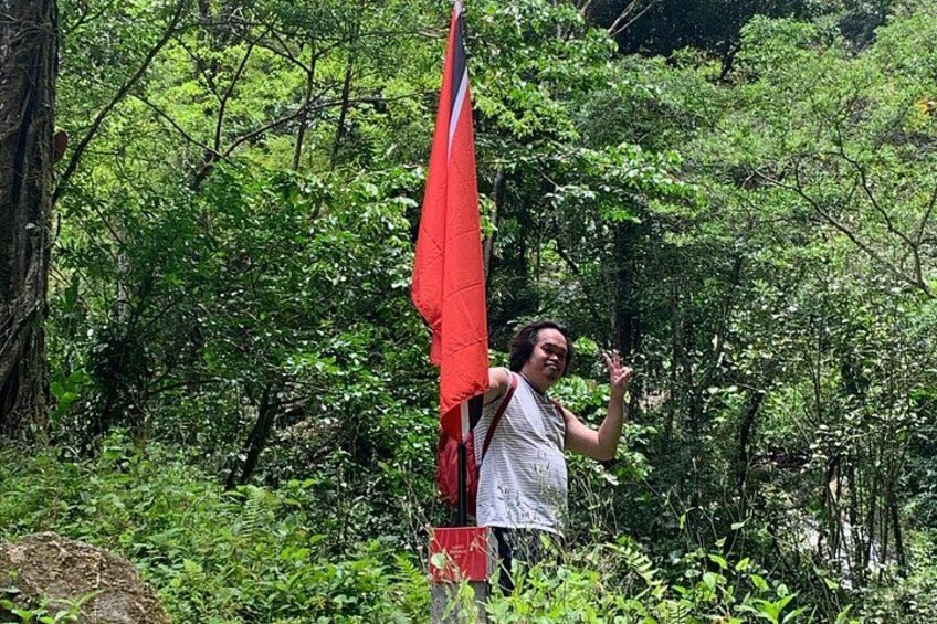 A person standing in a forested area with dense green foliage. 2