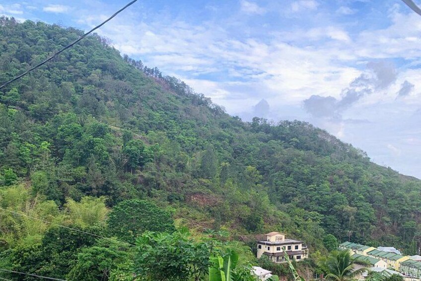 Une montagne verdoyante et luxuriante, couverte d’une végétation dense, un petit bâtiment et un ciel dégagé. 3