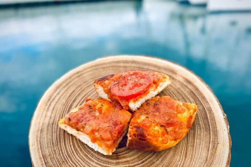 Three pieces of flatbread topped with tomato slices on a wooden plate. 5