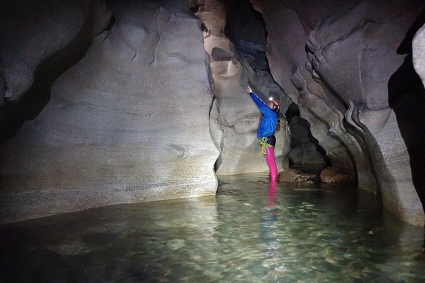 A person standing in a cave with water at the bottom. 5