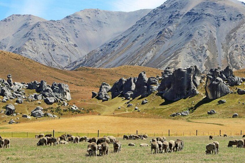 A mountainous landscape with rocky formations and a herd of sheep grazing. 4