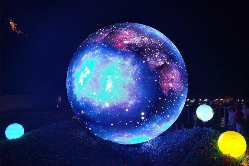 A large illuminated globe with a space-themed design, surrounded by smaller glowing spheres. 3