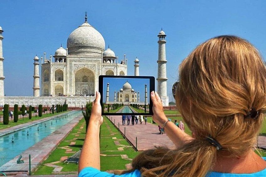 A person taking a photo of the Taj Mahal with a tablet. 5