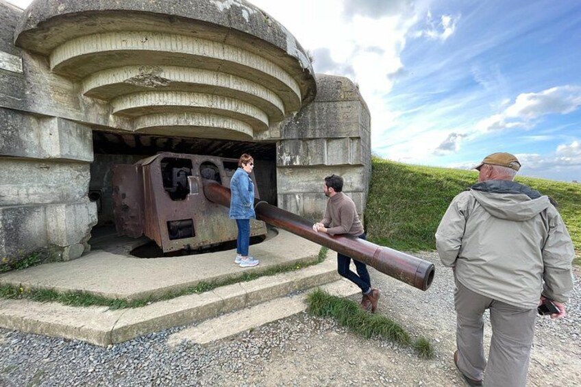 Un cañón grande frente a una estructura de concreto, con gente parada cerca. 3