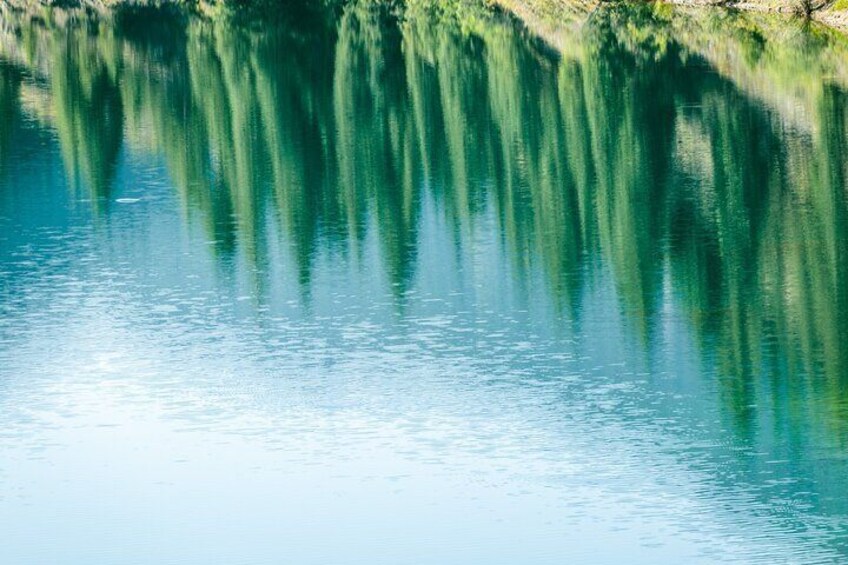 A calm lake with reflections of trees and a clear sky. 4