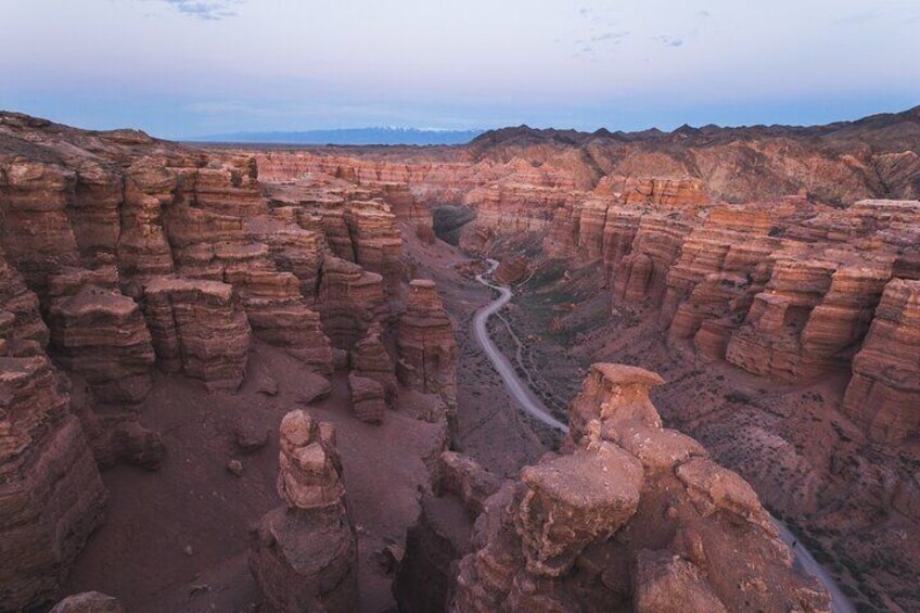A canyon with layered rock formations and a winding road. 1
