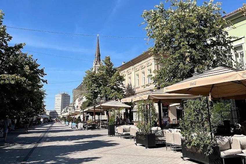 A street lined with outdoor cafes, a church spire, and buildings with classical architecture. 3