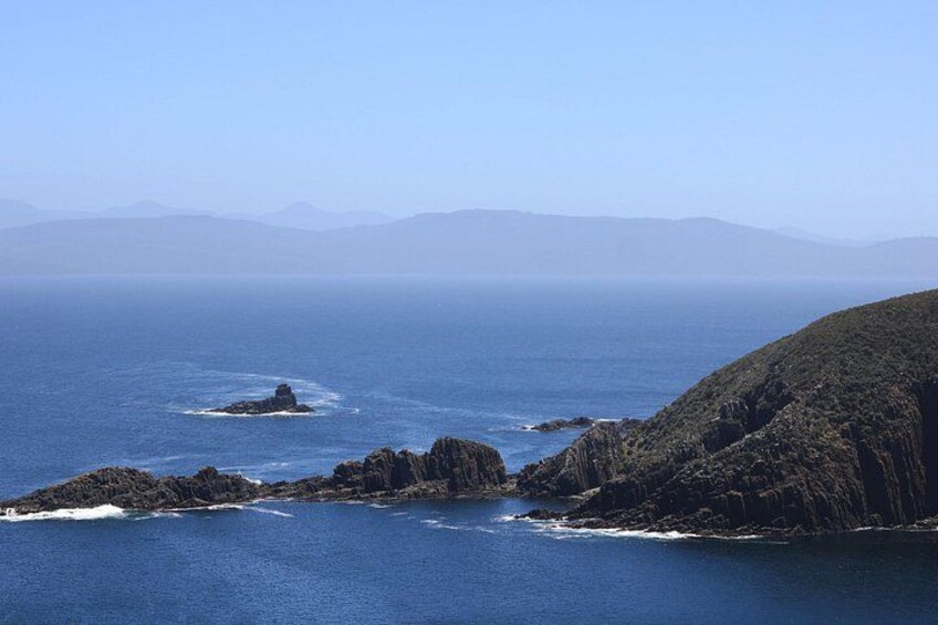 A coastal landscape with rocky outcrops and calm sea. 3