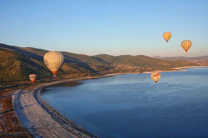 Een kustlandschap met luchtballonnen, een strand en glooiende heuvels. 2
