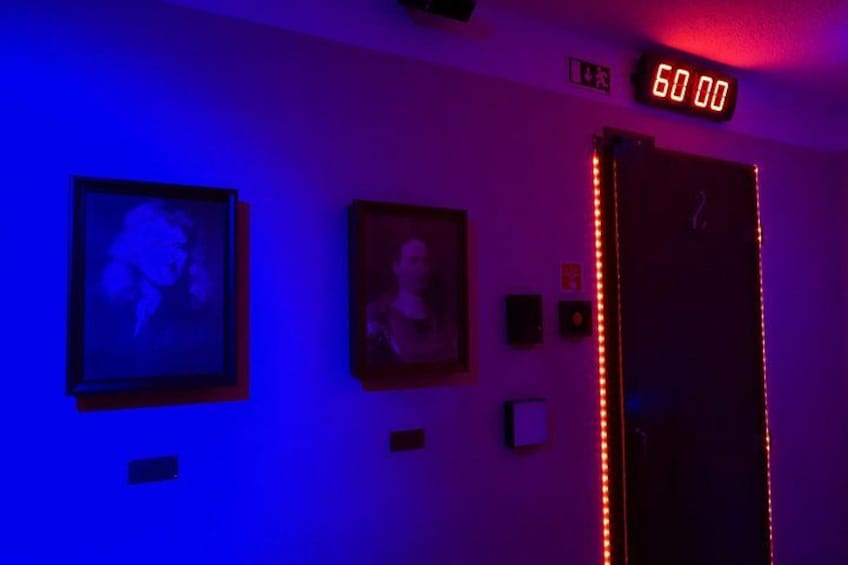 A room with two framed pictures on the wall, a digital clock displaying '50:00', and a door with red LED lights. 3