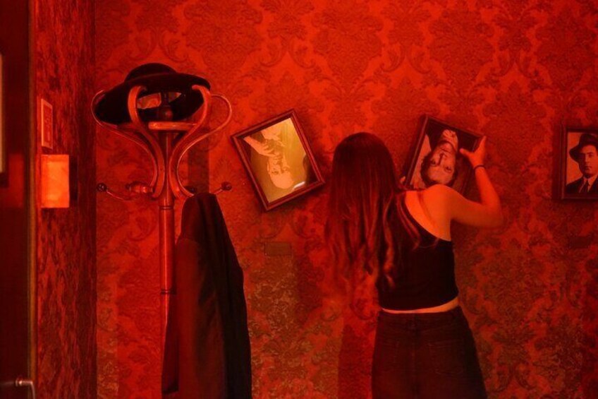 A person hanging pictures on a wall with a patterned wallpaper background. 4