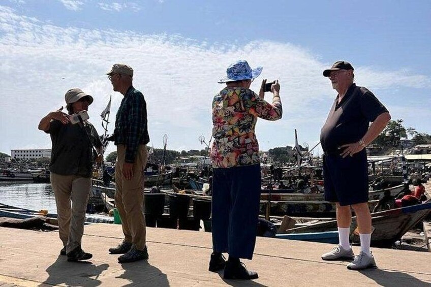 A group of people standing on a dock by a marina with boats in the background. 2