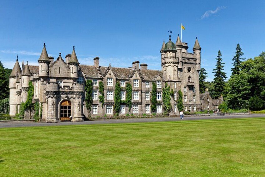 A large, historic castle with multiple towers and a well-maintained lawn in front. 1