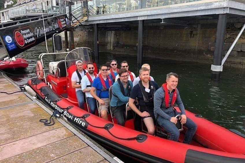 Un grupo de personas en un barco rojo llamado 'Citi Harbour Boat Hire' amarrado en un muelle. 1